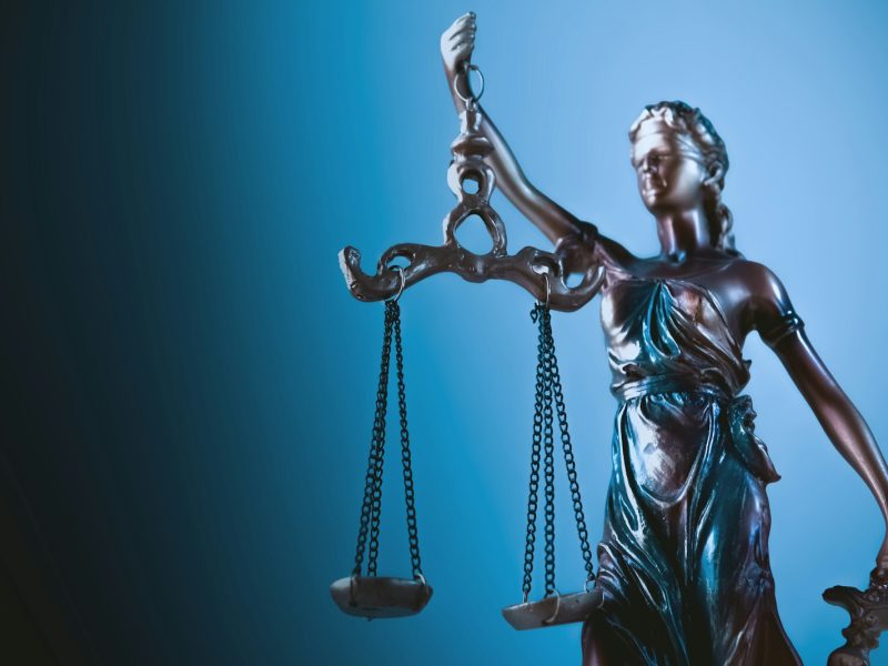 Statue de la Justice tenant sa balance, sur fond bleu