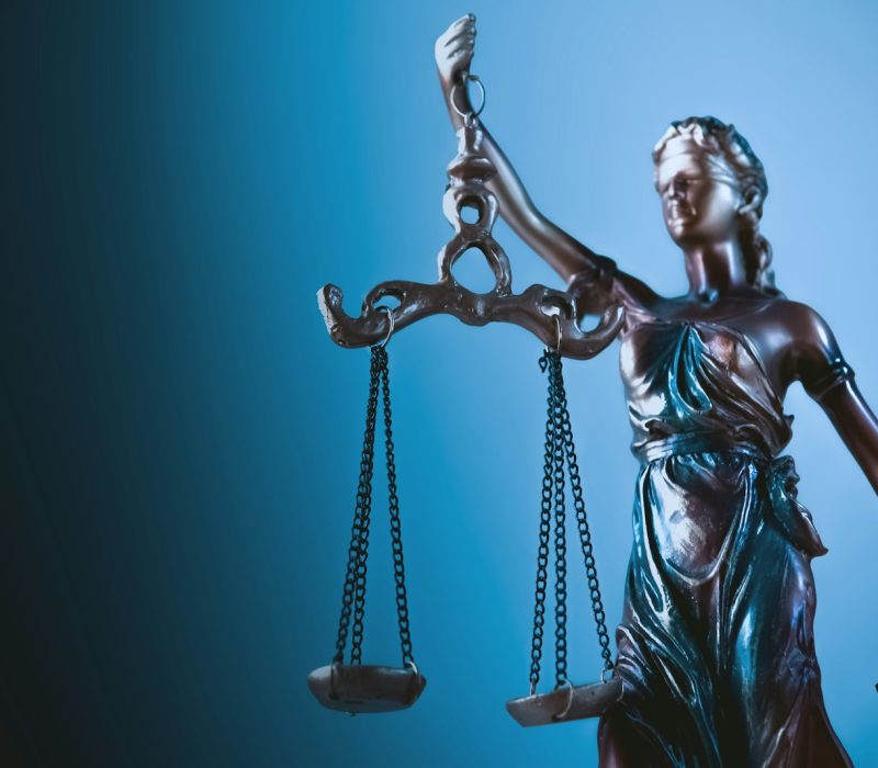 Statue de la Justice tenant sa balance, sur fond bleu