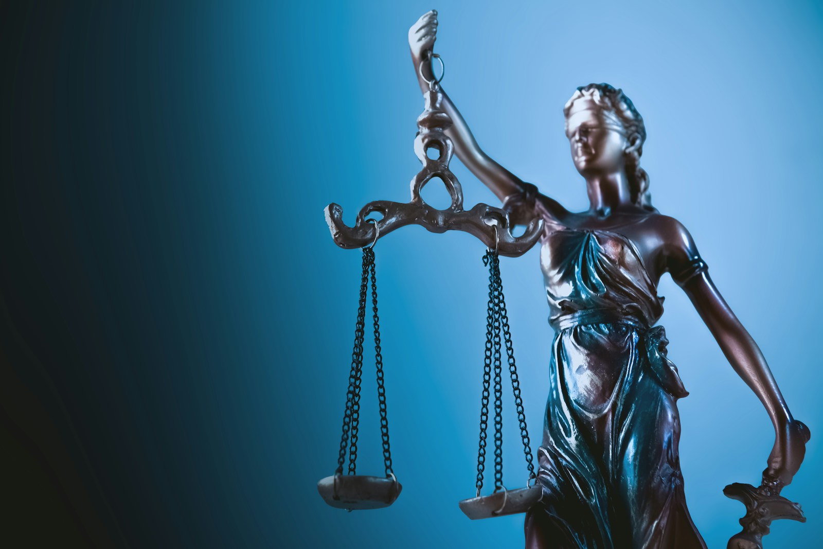 Statue de la Justice tenant sa balance, sur fond bleu