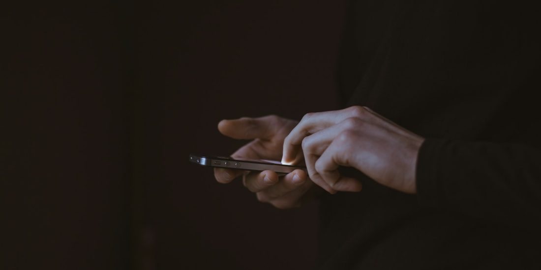 Silhouette d'une personne tenant un smartphone, à contre-jour