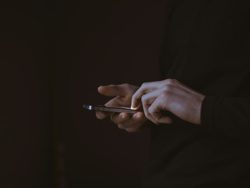 Silhouette d'une personne tenant un smartphone, à contre-jour