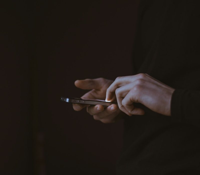 Silhouette d'une personne tenant un smartphone, à contre-jour