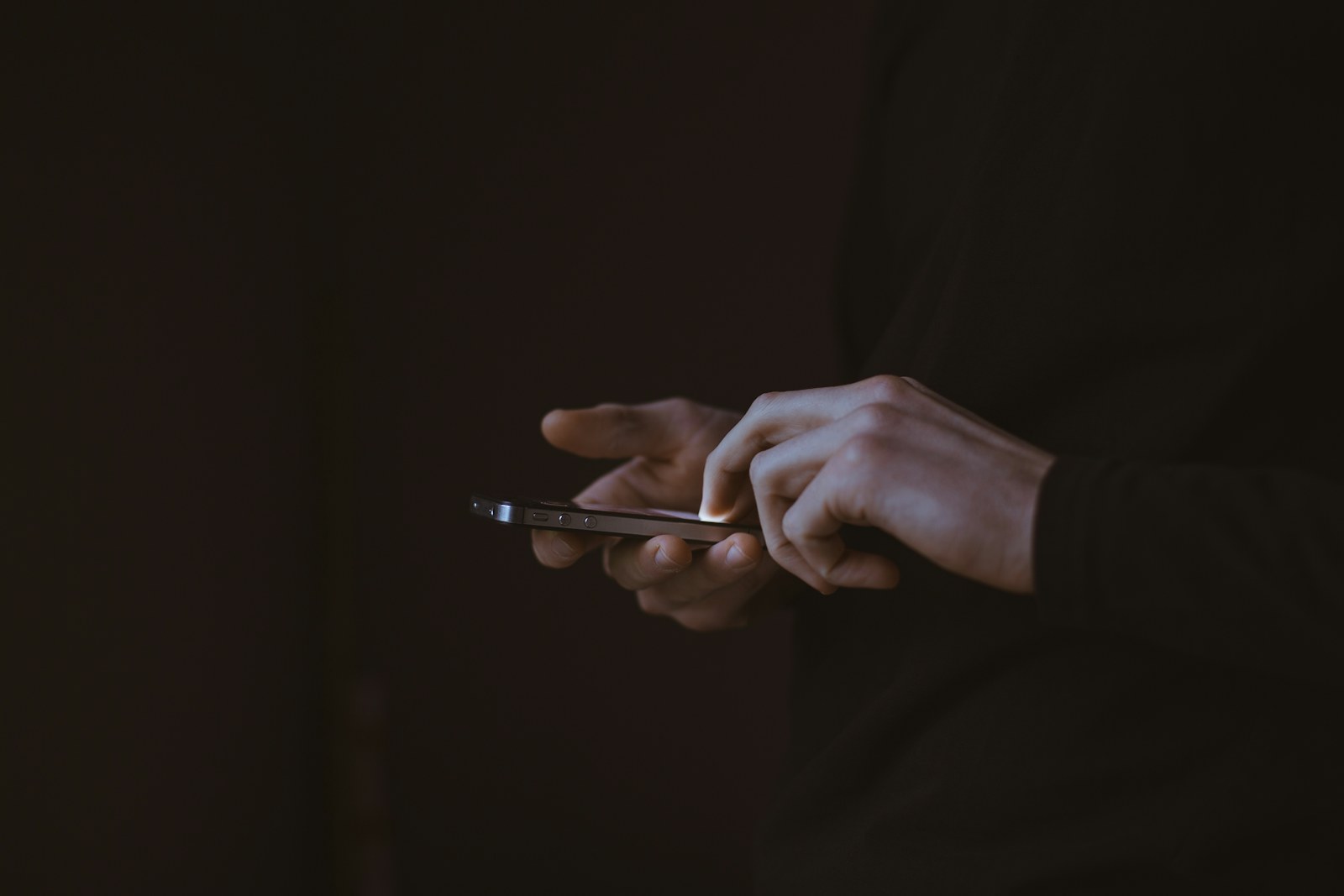 Silhouette d'une personne tenant un smartphone, à contre-jour